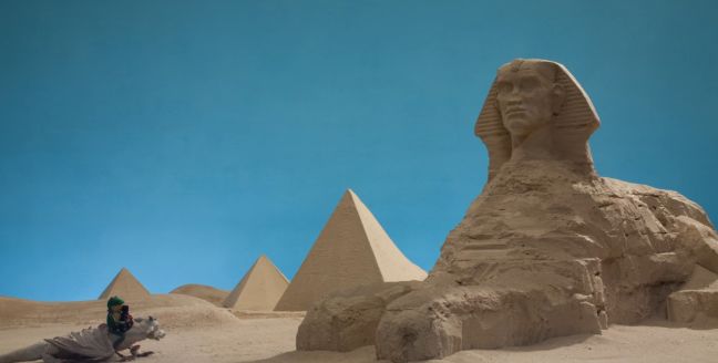 Frosch und Drache stehen vor der Sphinx in der Wüste