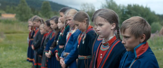 Eine Gruppe Sámi-Kinder im Gákti sind draußen und stehen in einer Reihe
