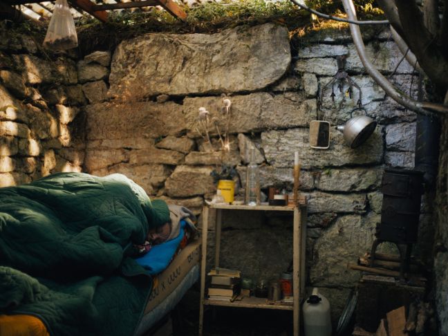 Patty liegt in einem Bett in einer offenen Hütte im Wald