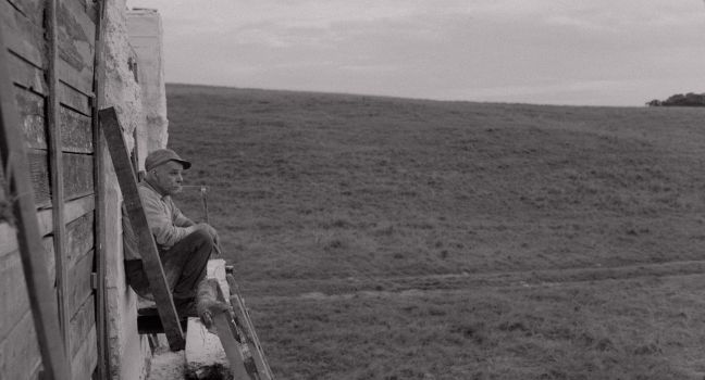 Karl-Göran lehnt an der Mauer und schaut Richtung Feld