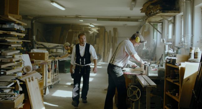 Paul geht durch die Tischlerei an Maschinen und Kollegen vorbei