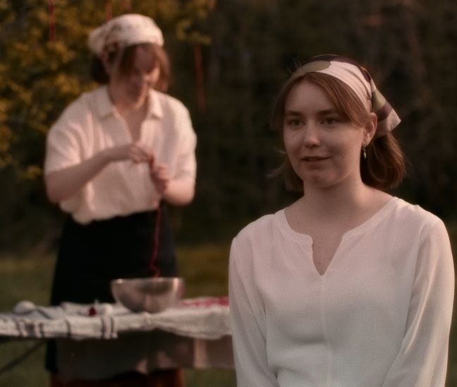 Eine der Schwestern erzählt über die Ernte, während die andere im Hintergrund die „Früchte“ vorbereitet