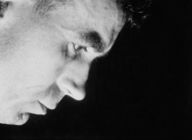 Mann schaut nach unten vor schwarzem Hintergrund