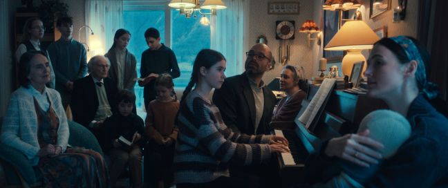 Die Familie sitzt singend um das Klavier im Wohnzimmer