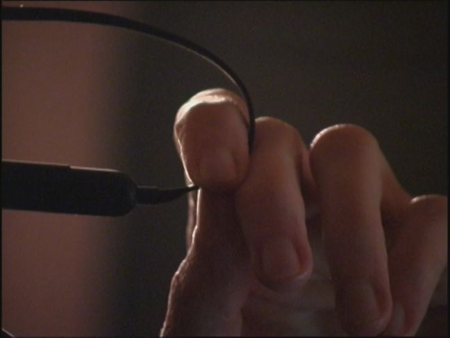 eine Hand mit einem Kabel zwischen den Fingern