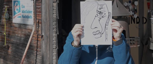 ein Mensch hält eine abstrakte Zeichnung eines Gesichts vor sich