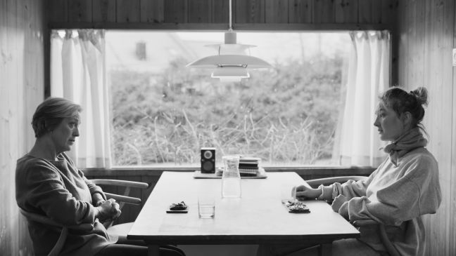 Mutter und Tochter sitzen sich am Küchentisch gegenüber