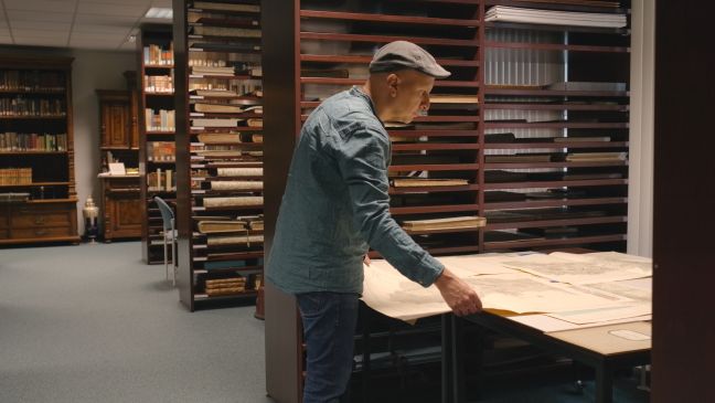 Dario ist in eine Archiv und guckt sich Karten an