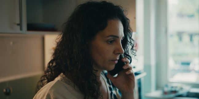 Teresa mit ernstem Blick  telefoniert mit dem Smartphone in der Küche