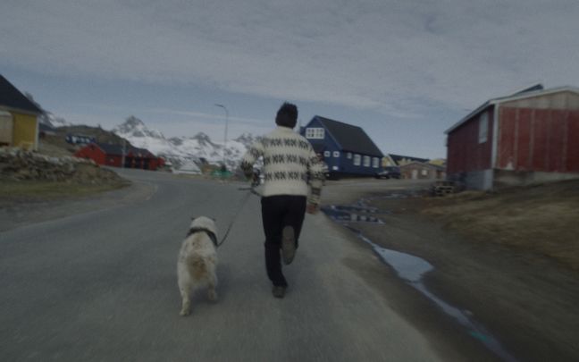 Kaali und sein Hund laufen auf der Straße; im Hintergrund sind Berge