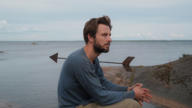 Vater sitzt kontemplativ im Hintergrund das Meer