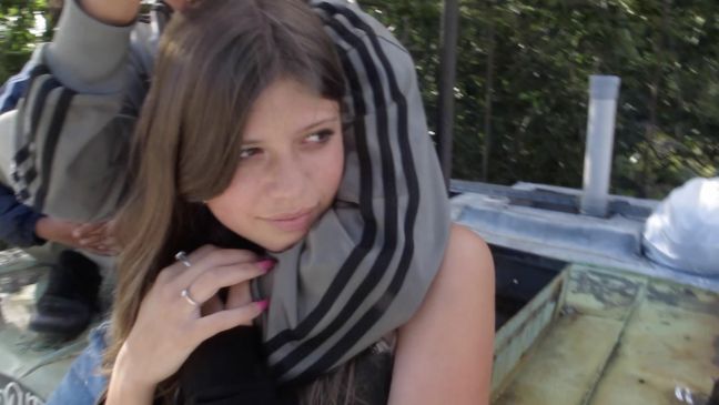 Jasmin wird von hinten umarmt und guckt in die Ferne an der Kamera vorbei