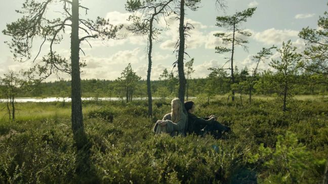 Emilie und Morten stützen sich sitzend an einen Baum
