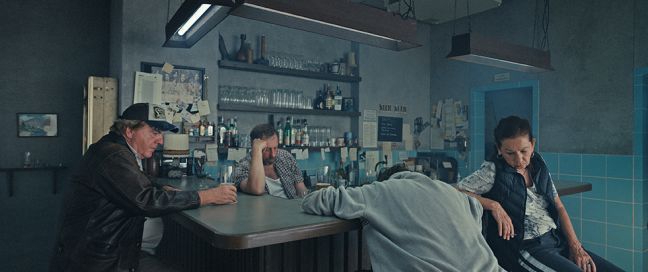 vier Menschen sitzen betreten in einer Kneipe