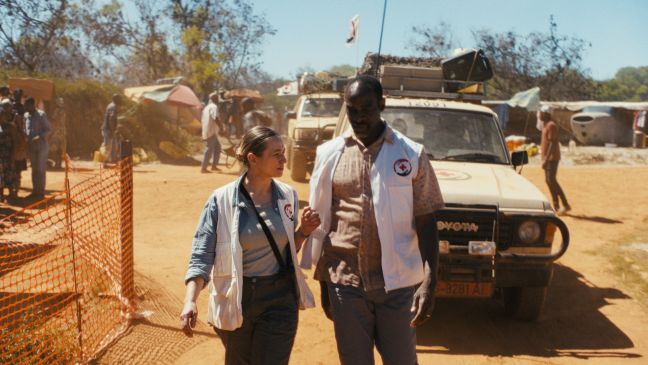 Zwei Ärzt:innen ohne Grenzen im Gespräch vor mehreren Jeeps