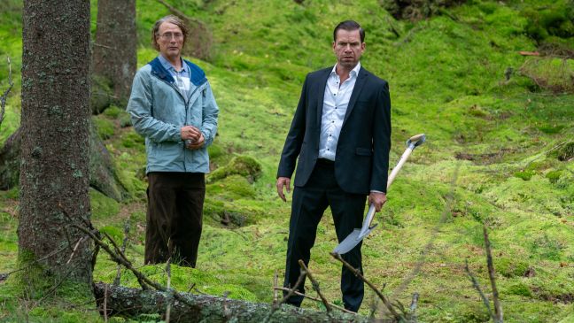 Manfred und Anker (mit Schaufel) stehen im Wald