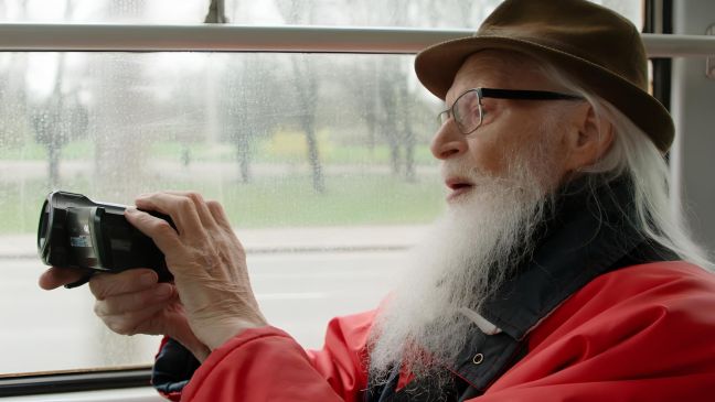 Margers im Bus im Profil, filmt frontal