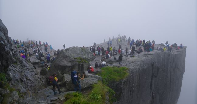 Im Nebel stehen Menschengruppen an einem Abgrund