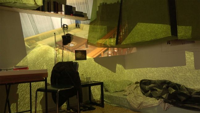 Eine Matratze auf dem Boden, auf die Wände sind mehrere Bilder projeziert