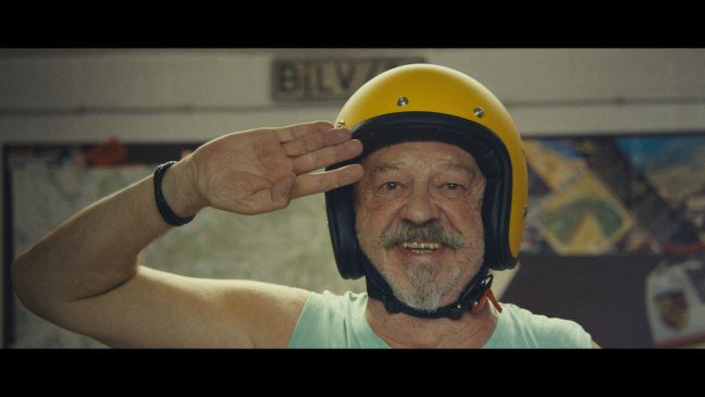 Paule mit gelbem Helm macht den militärischen Gruß und lächelt