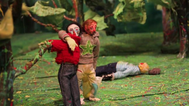 Zwei Figuren stehen im Park, eine liegt auf dem Boden