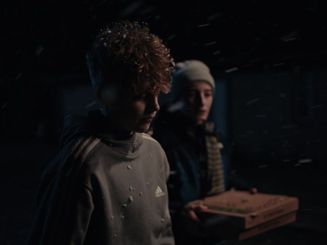 Felix mit Schnee im Haar, Anton mit Pizzakartons hinter ihm