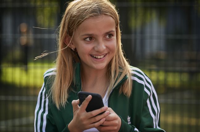 Honey lächelt, Handy in der Hand