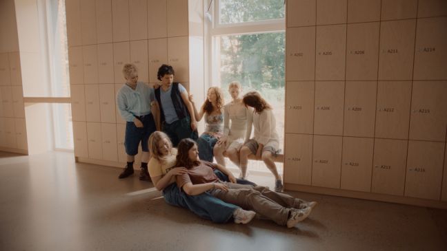 Tänzer*innengruppe sind im Körperkontakt auf dem Schulflur