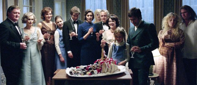 Die Familie mit Sektgläsern steht um eine geschmückte Platte mit Süßigkeiten
